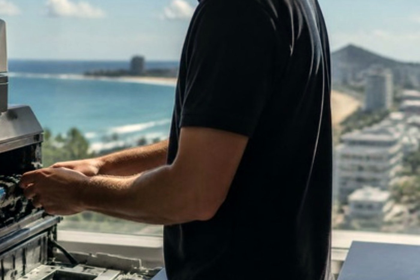 Technician servicing a copier beside a window in a bright Sunshine Coast office